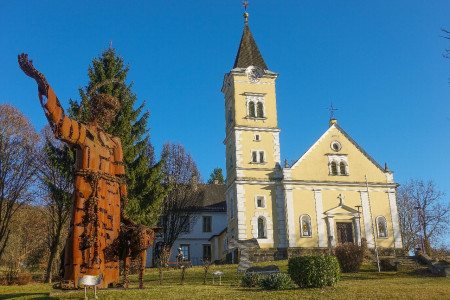 Franziskusstatue mit dem Wolf von Gubbio des bolivianischen Künstlers Fernando Crespo neben der Pfarrkirche Tieschen